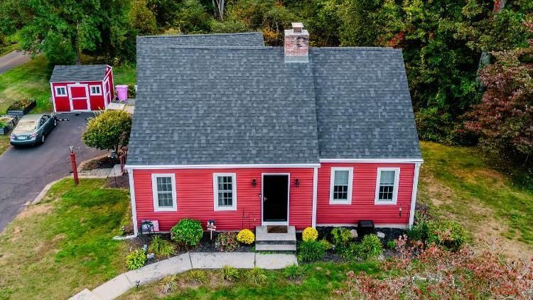 An aerial view of a red house with a asphalt roof
