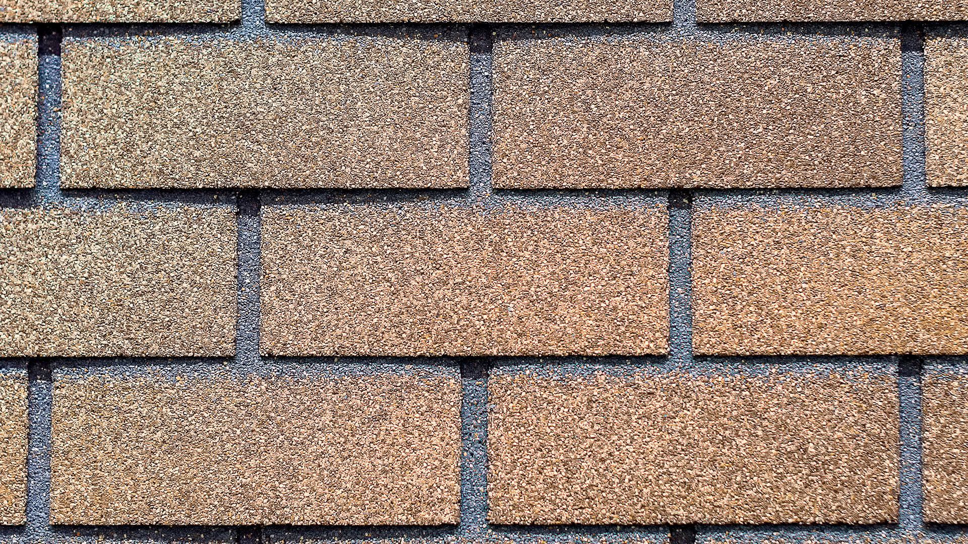 A close up of a brick wall with  3-tab shingles on it.