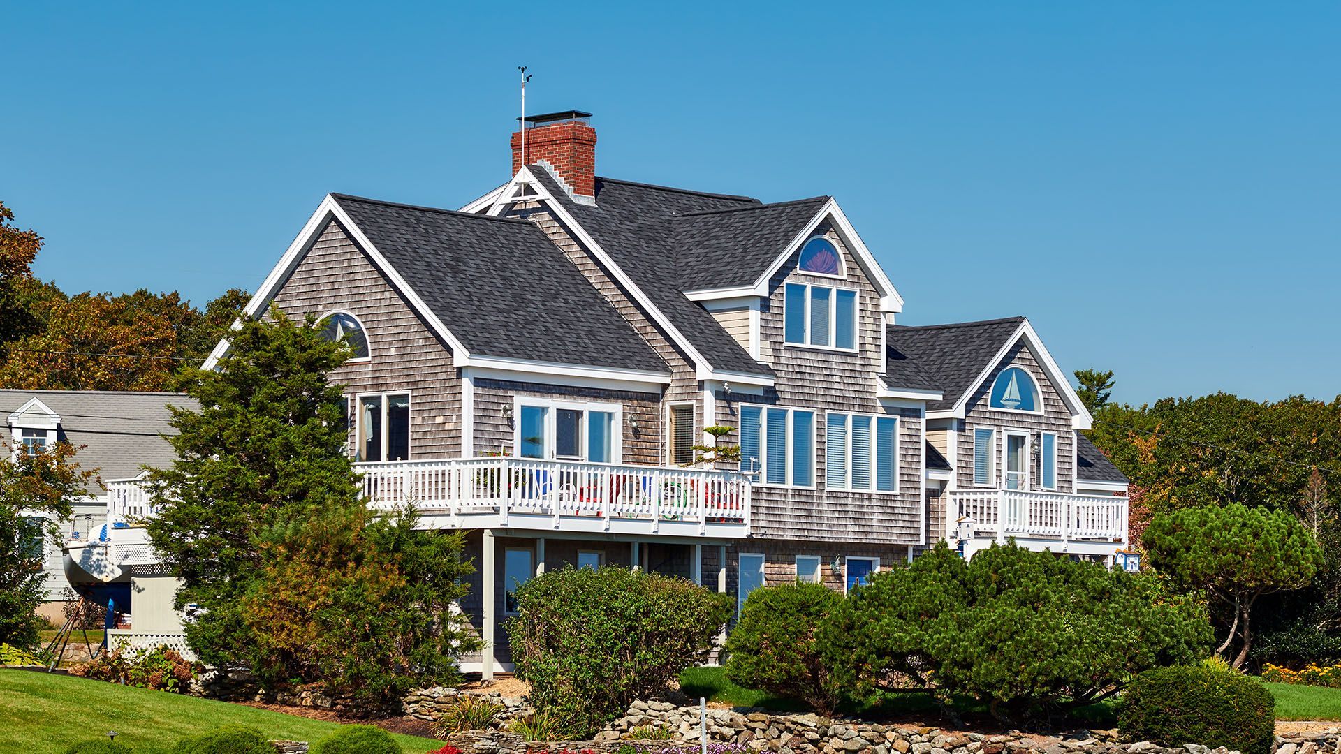 A large house is sitting on top of a lush green hill.