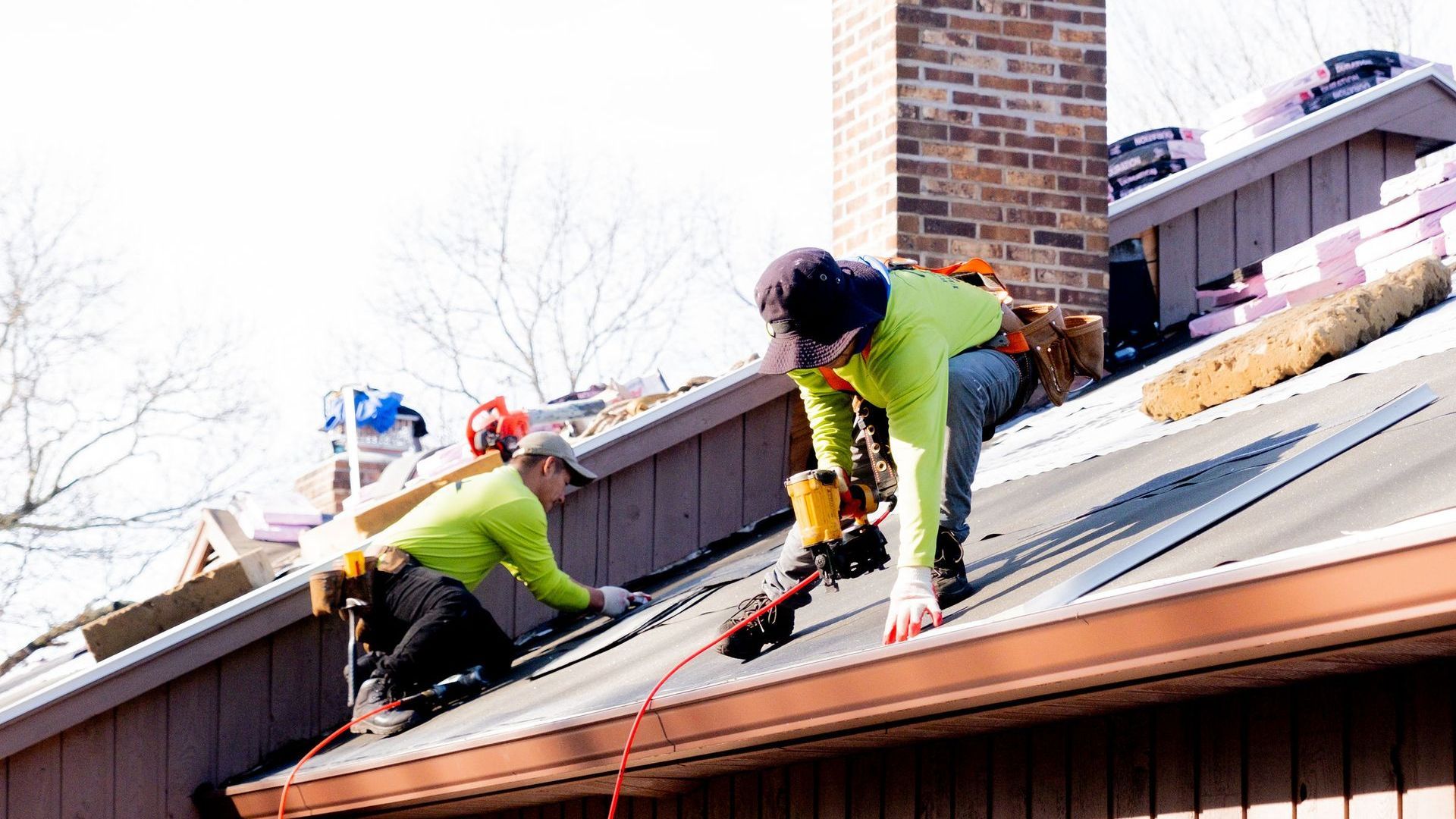 Two men are working on the roof of a house.
