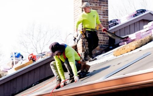 Two a1 home improvement contractors working on a roof leak on a house