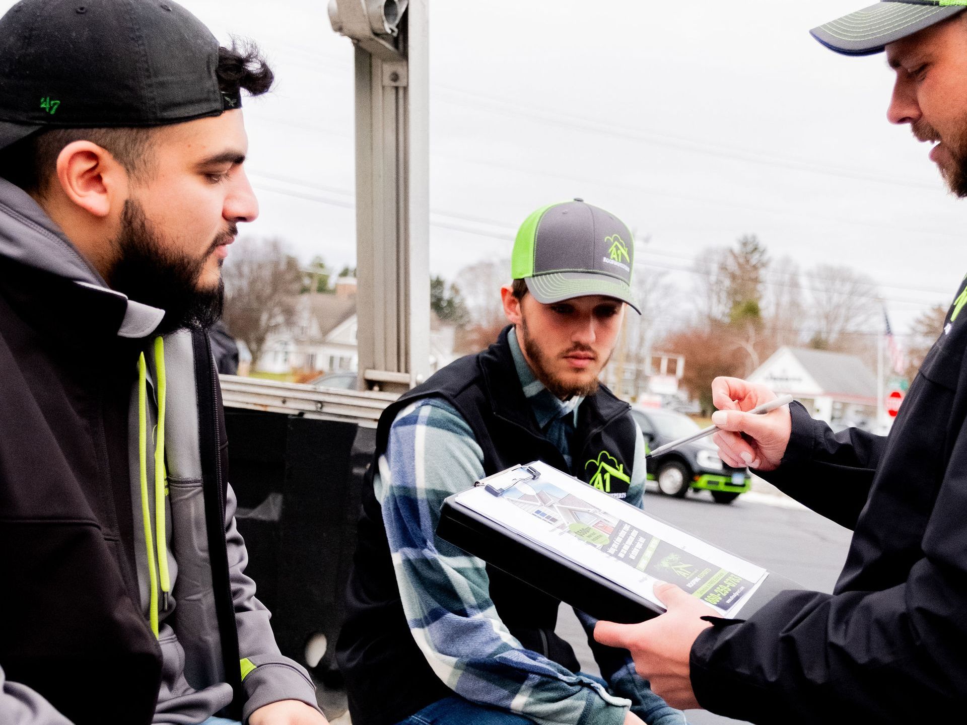 A group of men are sitting on a truck tailgate talking to each other.