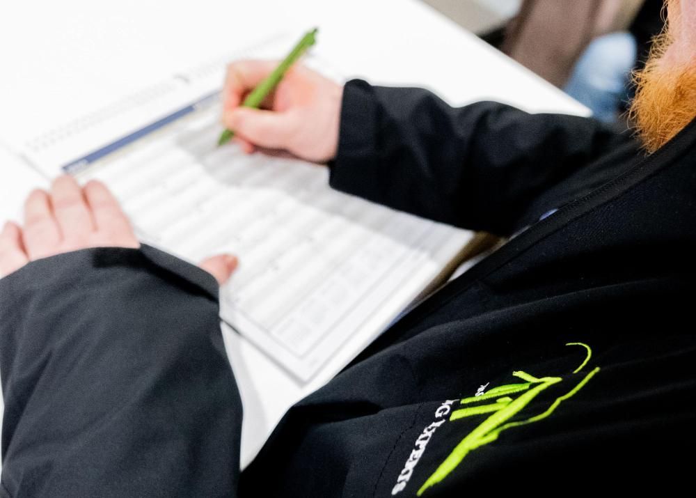 A man with a beard is estimating on a piece of paper the cost of a roof replacement