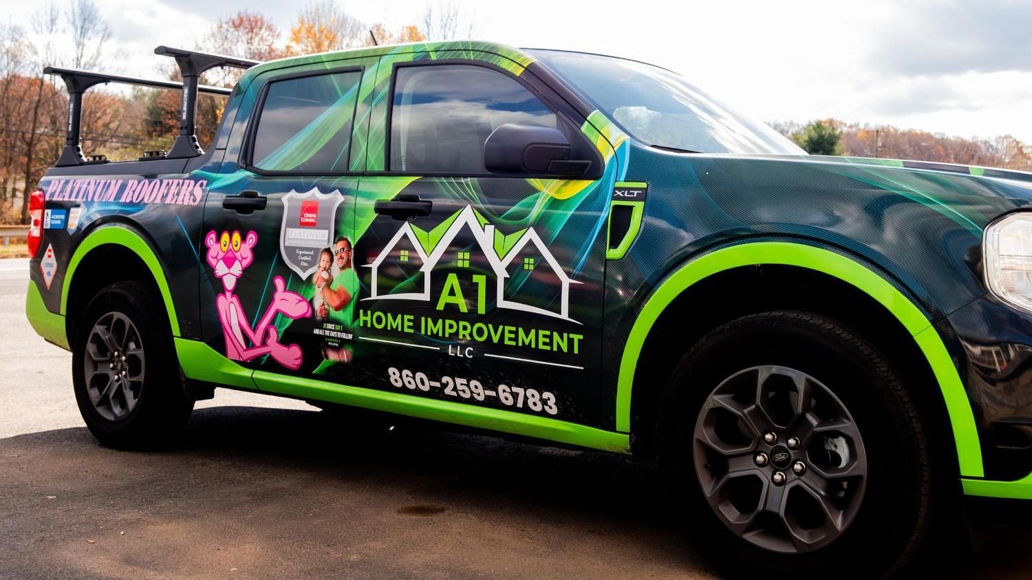 A green truck with a pink panther on the side is parked on the side of the road.