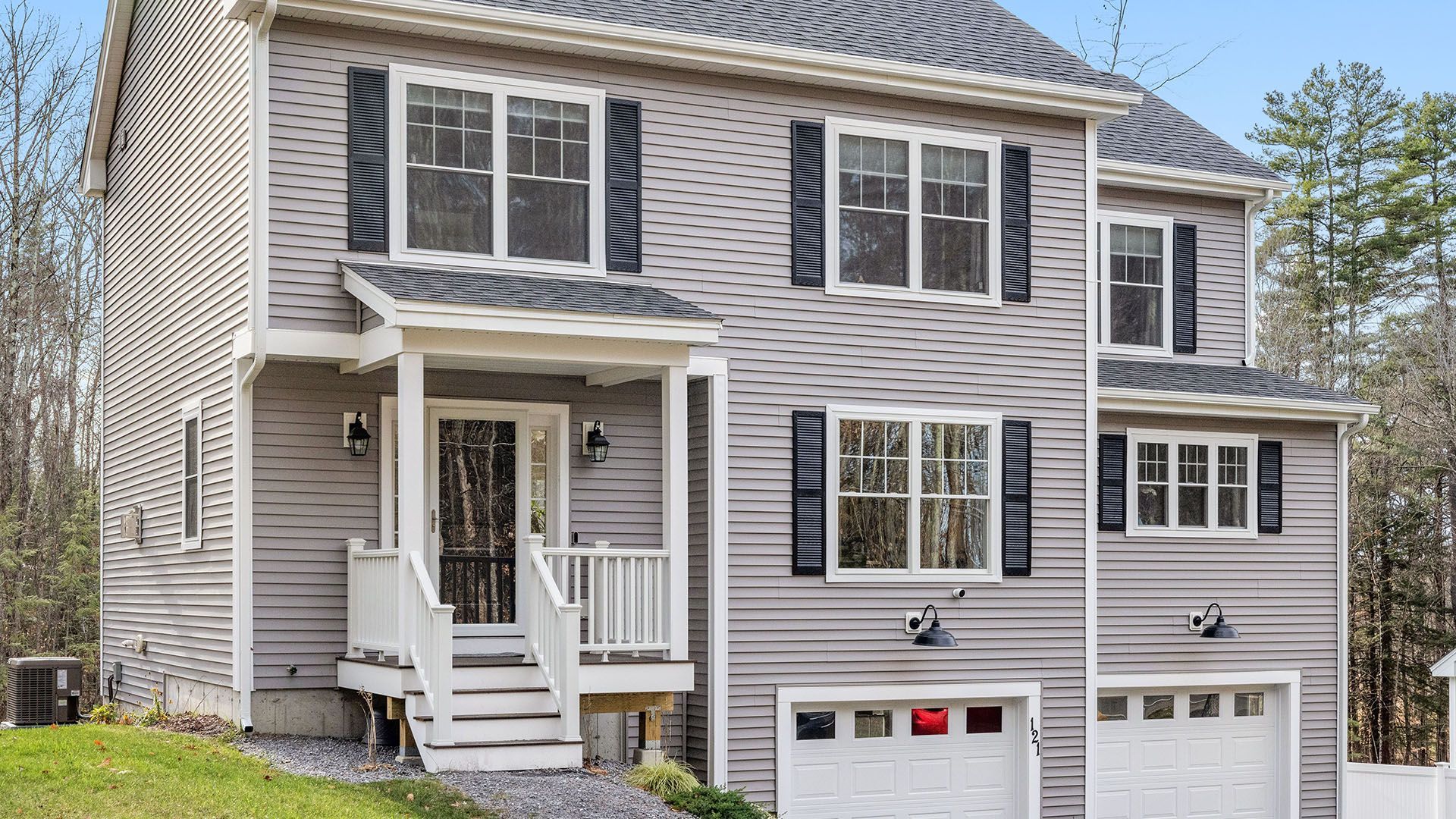 A large gray house with black shutters and a white porch.