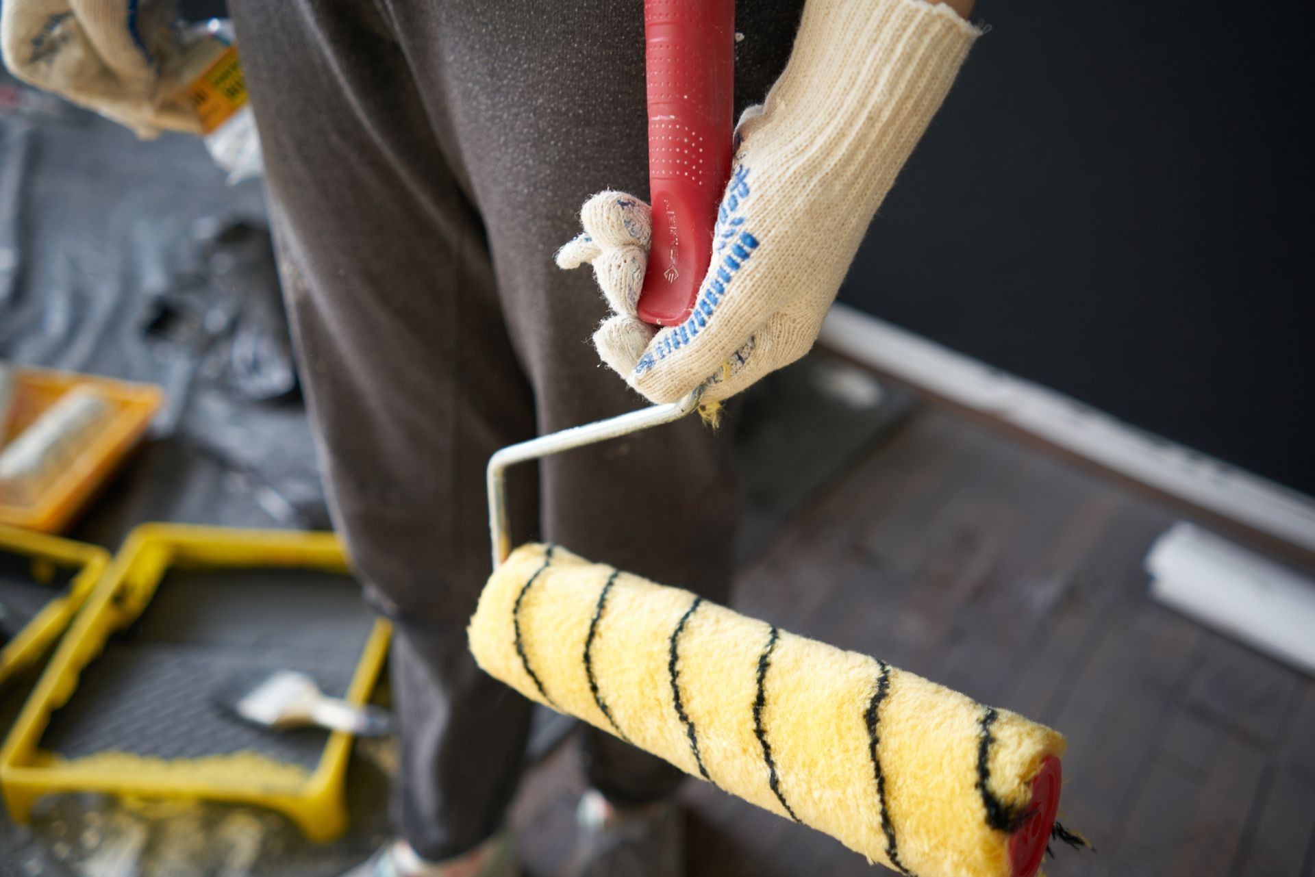 A person wearing gloves is holding a paint roller.