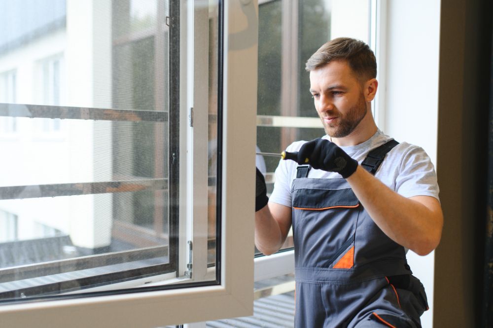 A man is installing a window in a house.