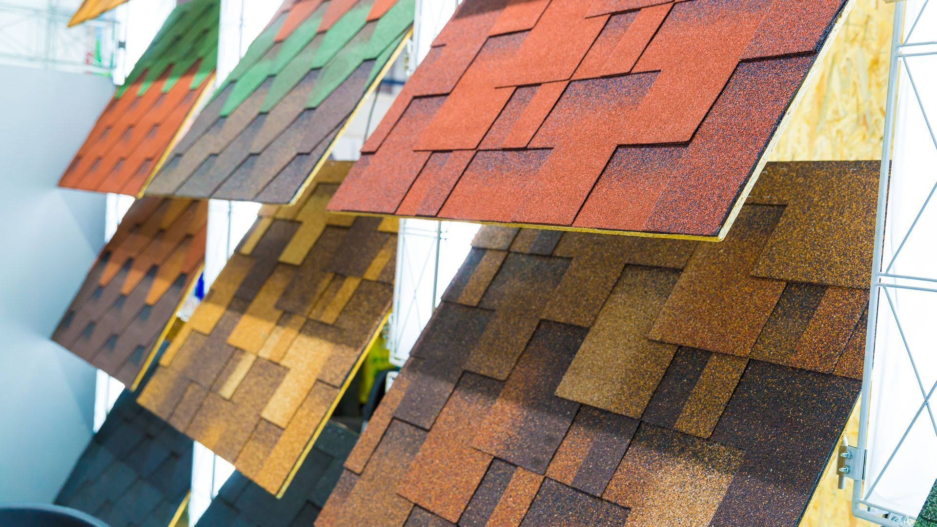 A row of different colored roof tiles hanging on a rack.