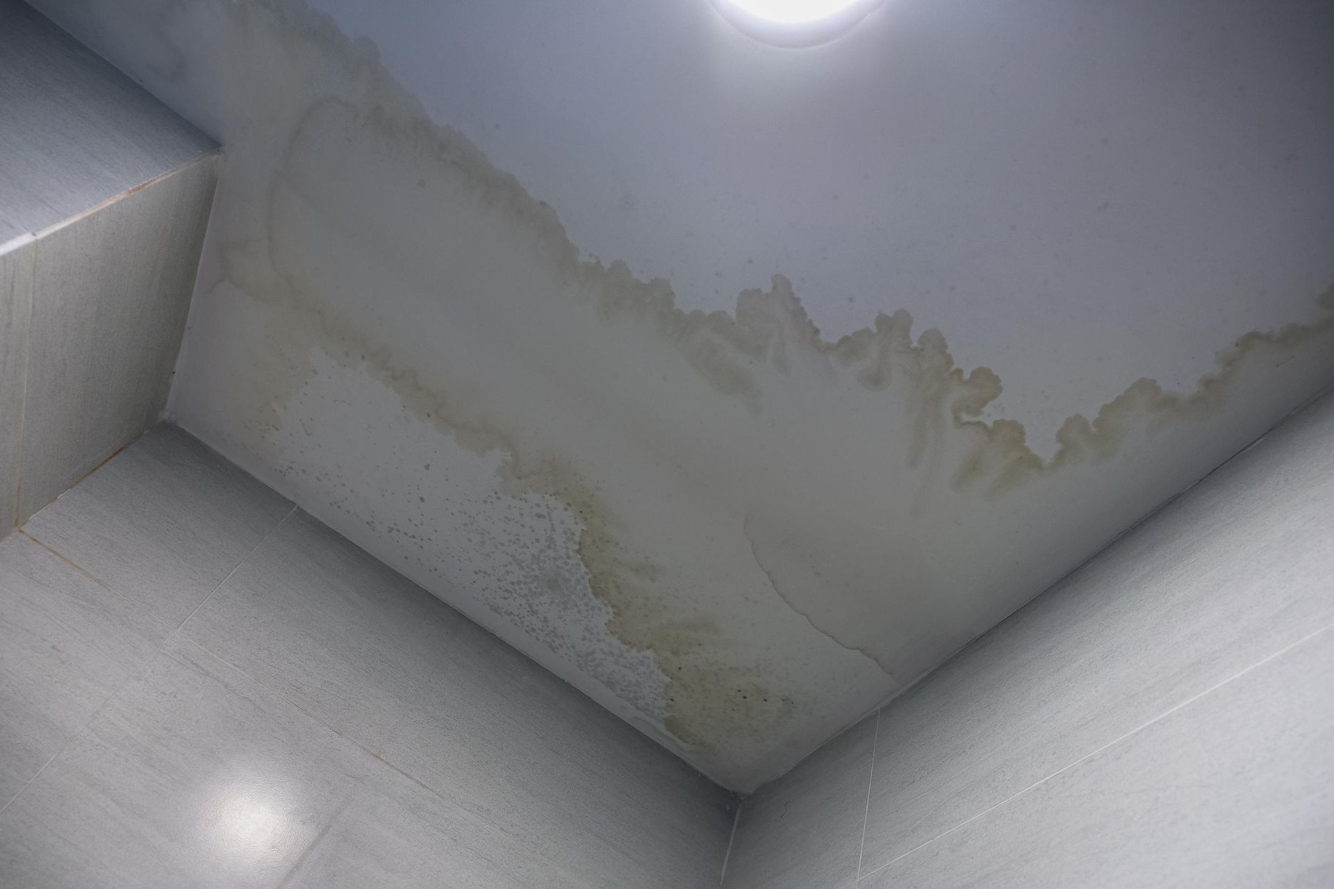 A room with a ceiling that has water stains on it.