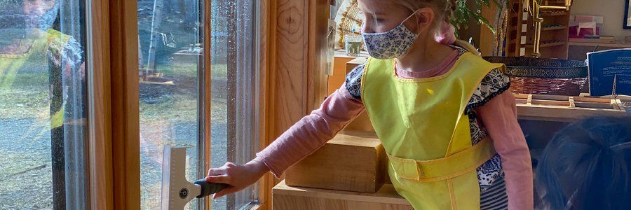 kindergarten aged child in smock by window with squeegee