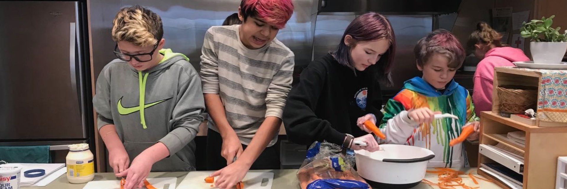 adolescent students peeling and cutting carrots