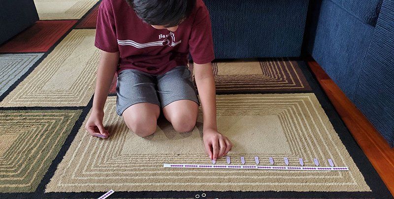 Boy on carpet with bead chain and number tags