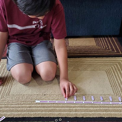 Elementary child with home bead chain lesson