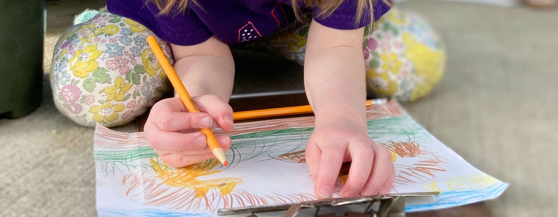 Close up of a child's hands drawing a picture with colored pencils