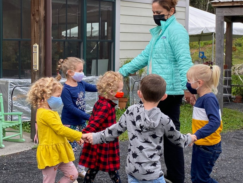 preschool children holding hands in a circle outdoors