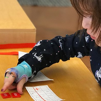 Young girl doing addition with 100s tiles