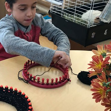 elementary first grade student with hand loom