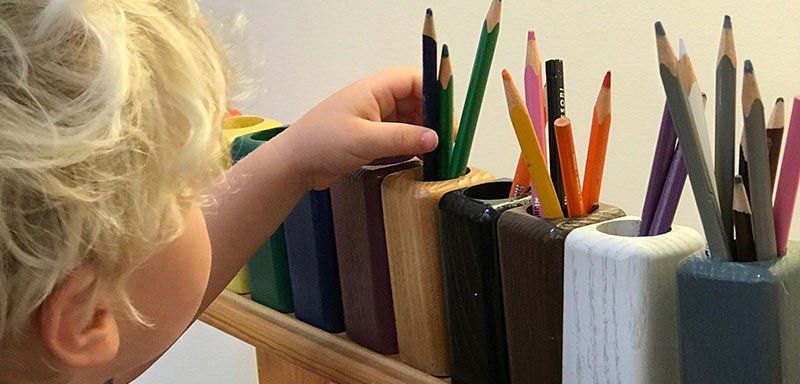 Preschool aged child choosing colored pencils from cups