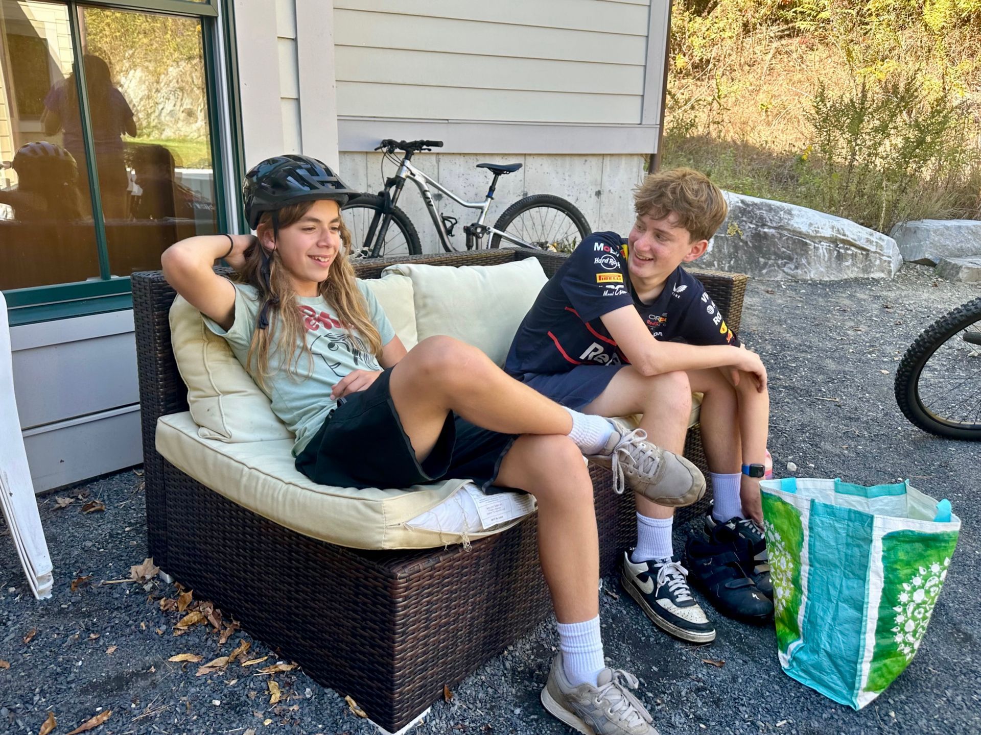 Image of two adolescent students sitting outdoors on a couch, talking