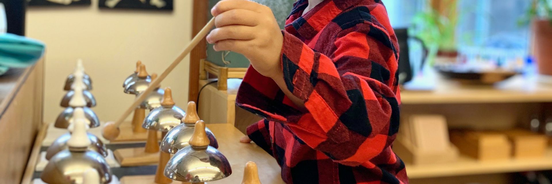 Image of a child with a small wooden mallet hitting tone bells