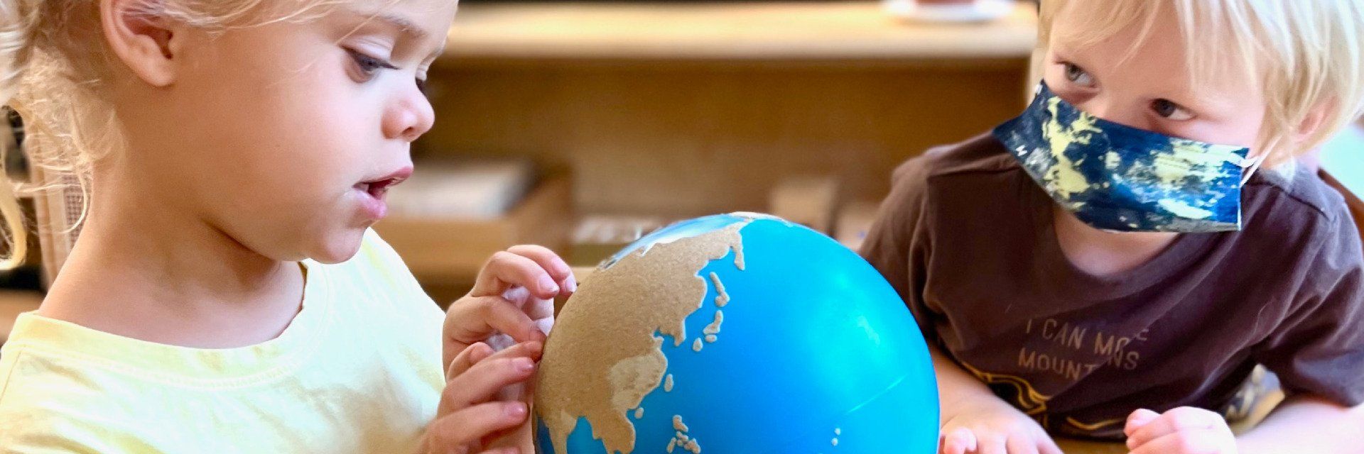 two pre-school aged children with a sandpaper globe