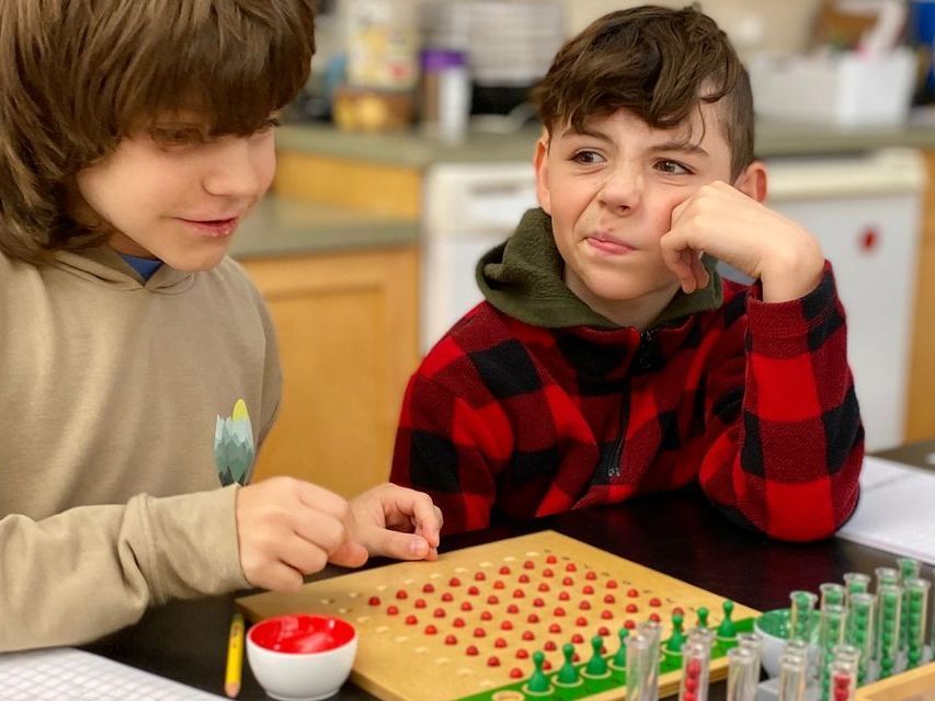 Two elementary aged students sitting at a table with the racks and tubes math lesson