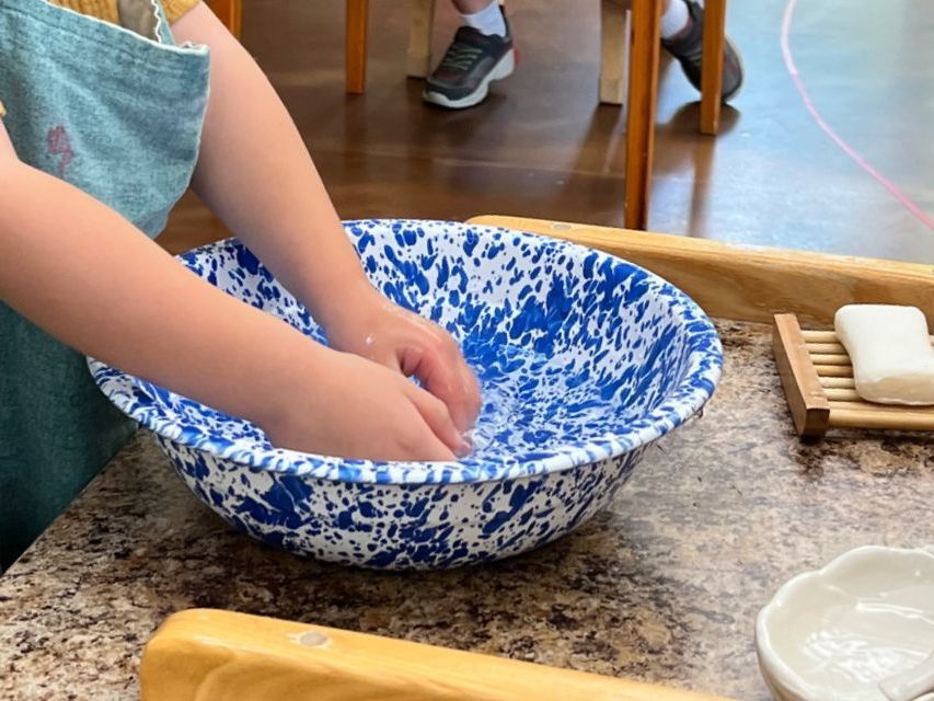 Image of a preschool child's hands using a basin to wash their hand