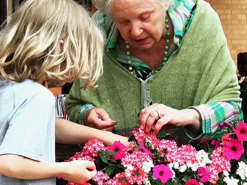 Image of an older woman and an elementary aged child dead-heading potted plants