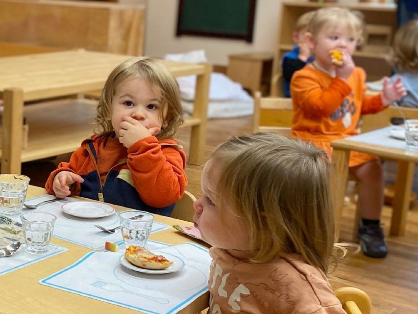 Image of toddlers sitting at set tables eating a meal together