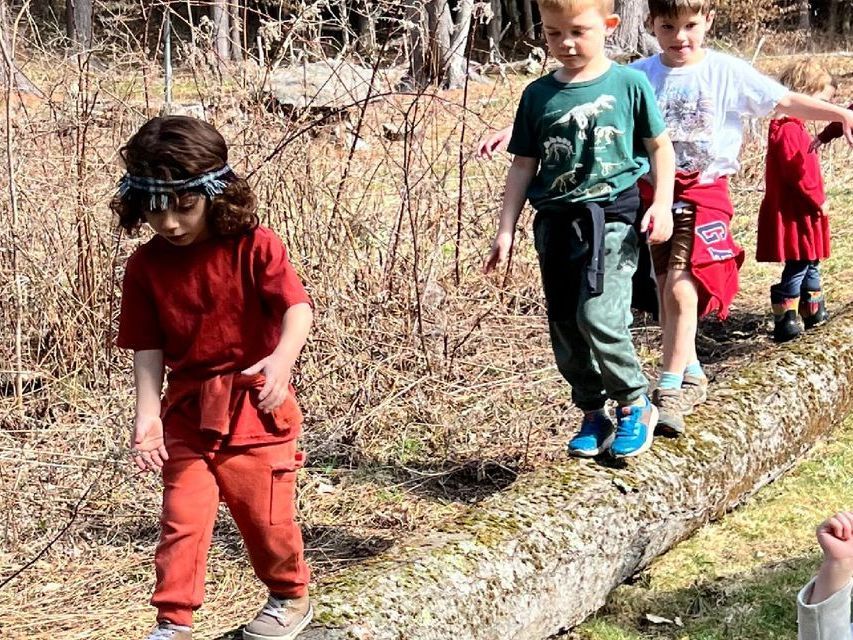 Image of preschool aged children walking across a log