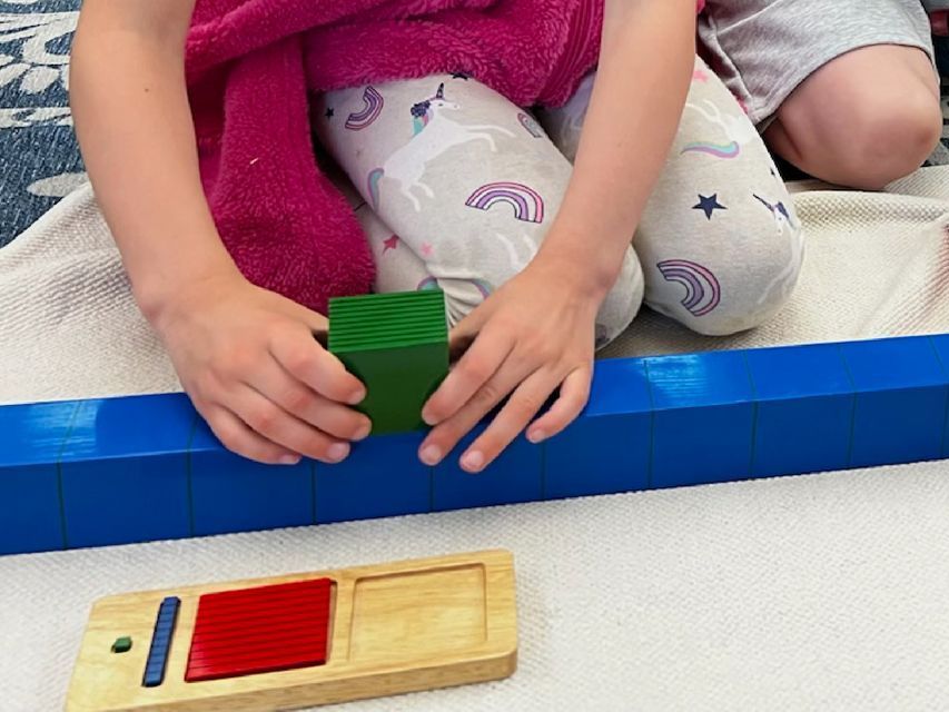 Image of a child using the wooden ten bar and unit cube from wooden heirarchical material