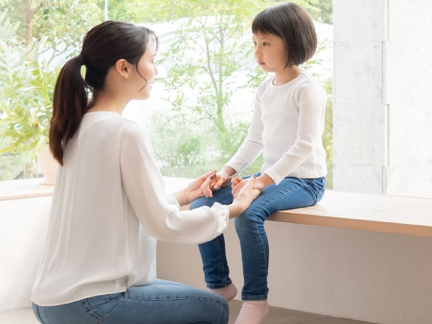 image of a child sitting on a bench with an adult kneeling in front of them