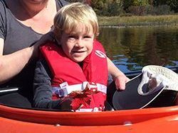 Close up shot of a young child and an adult paddling in a canoe