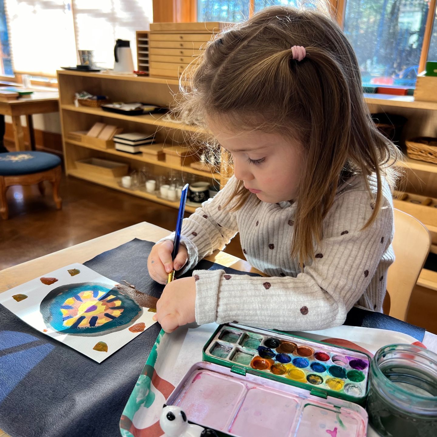 preschool child at a table working with watercolors