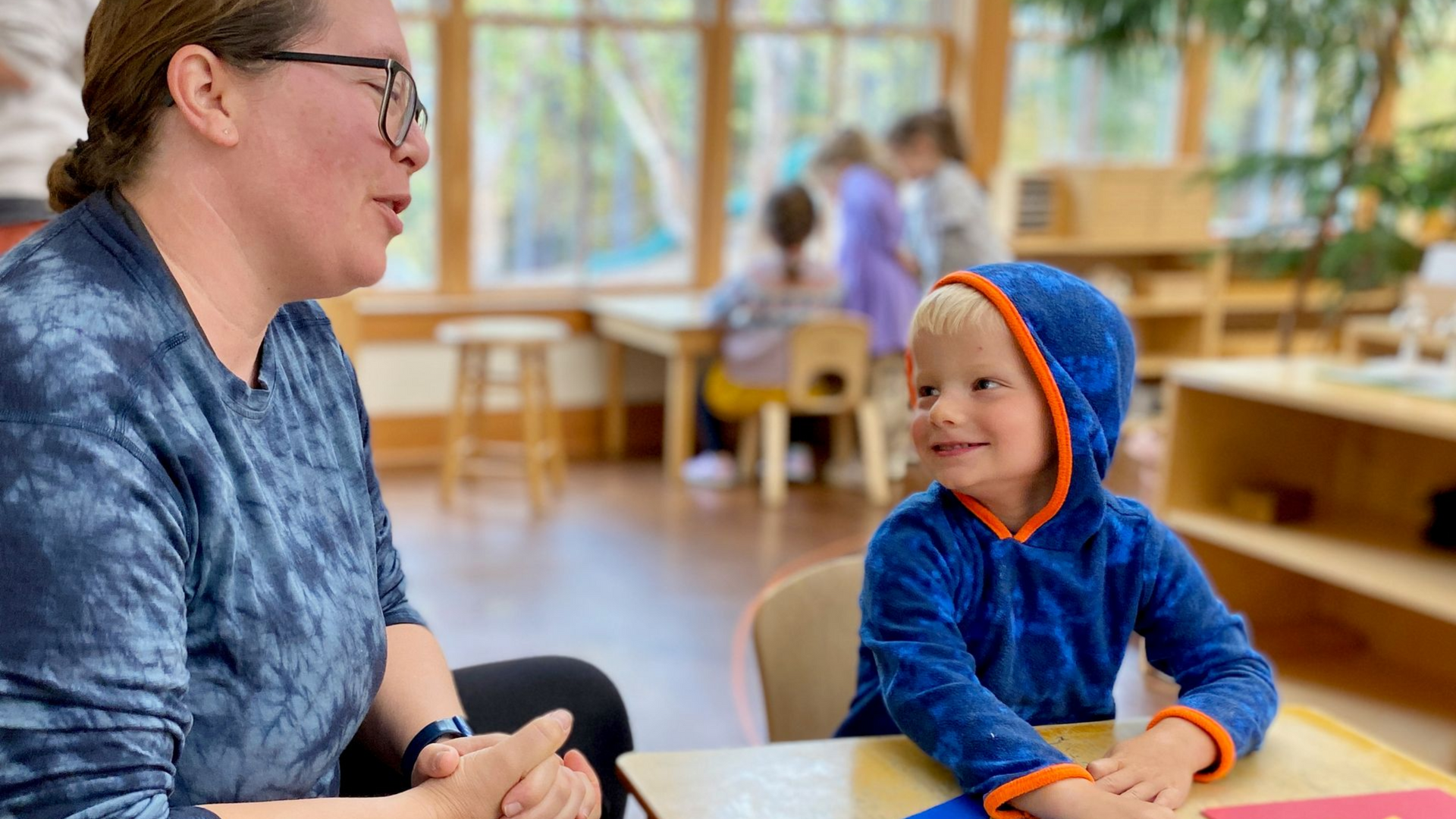 Image of an adult and child looking across a table at each other, smiling