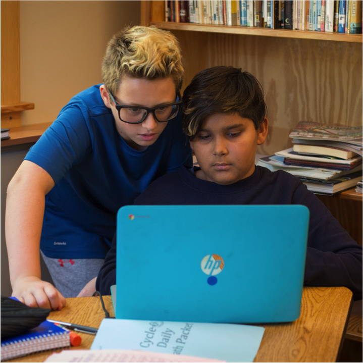 Two adolescent students looking at a laptop