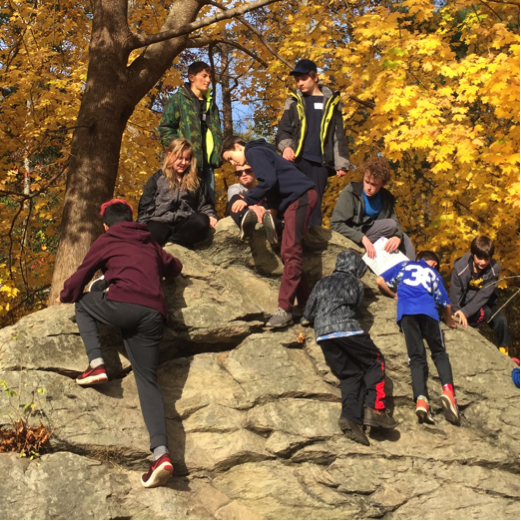 Group of middle school students climbing a large rock