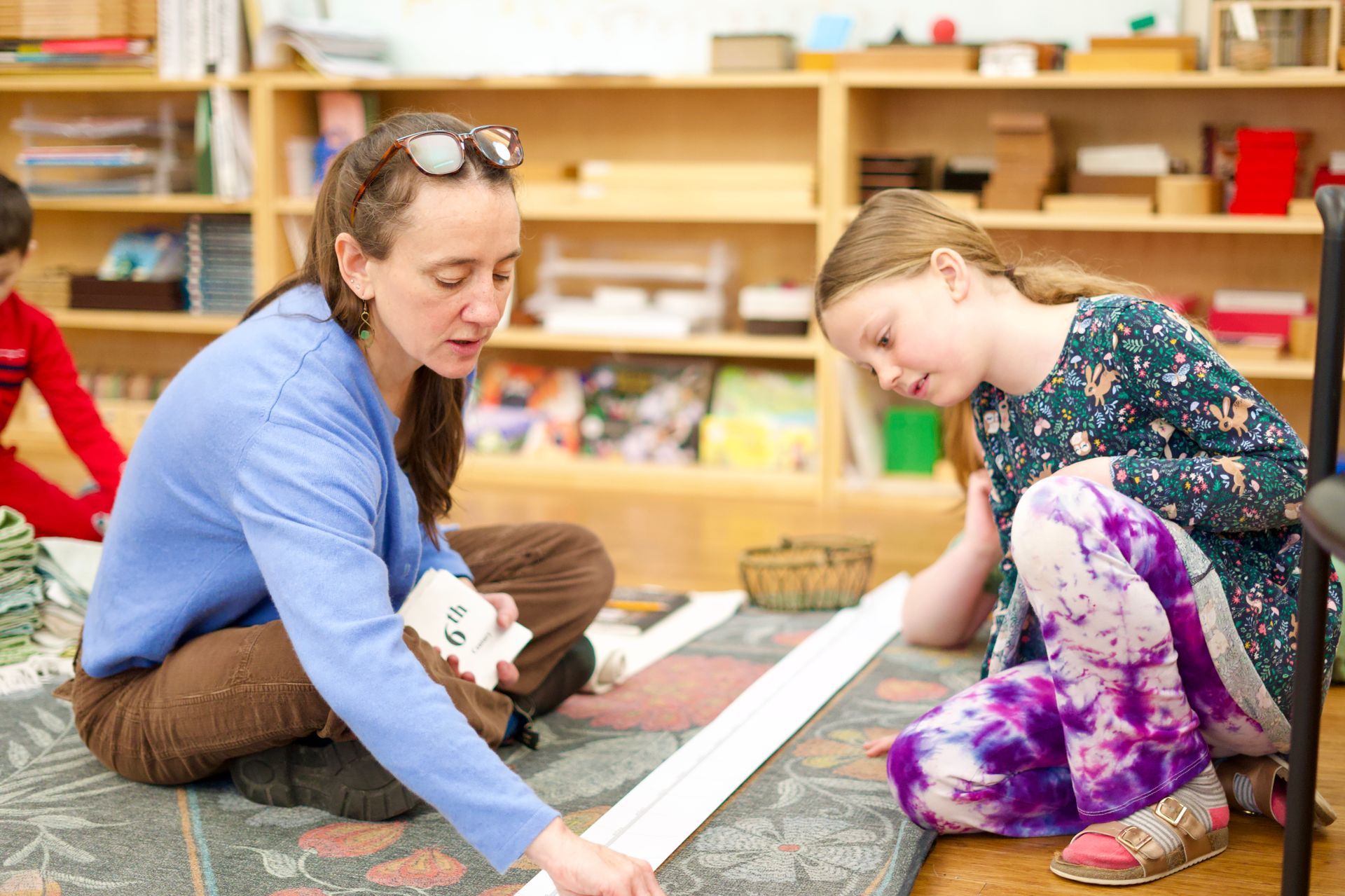 image of an adult and an elementary student sitting together on the floor reviewing a lesson