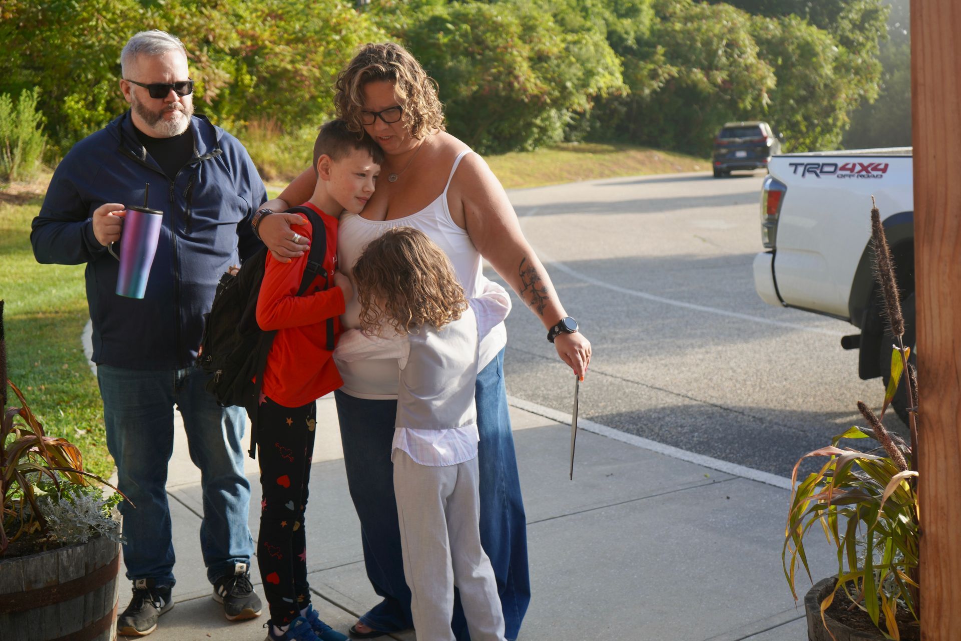 Image of two parents with two children hugging their children after school