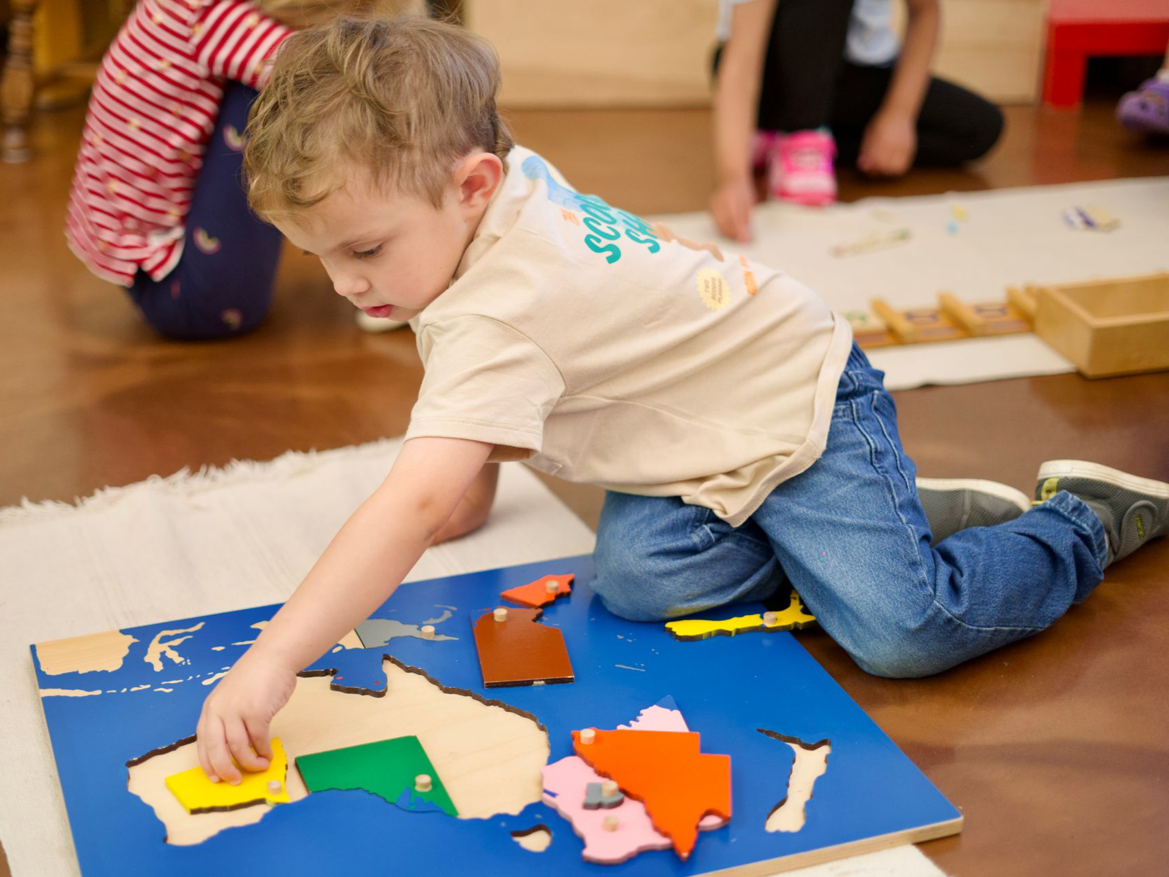 Preschool aged child sitting on the floor with a puzzle map of Australia