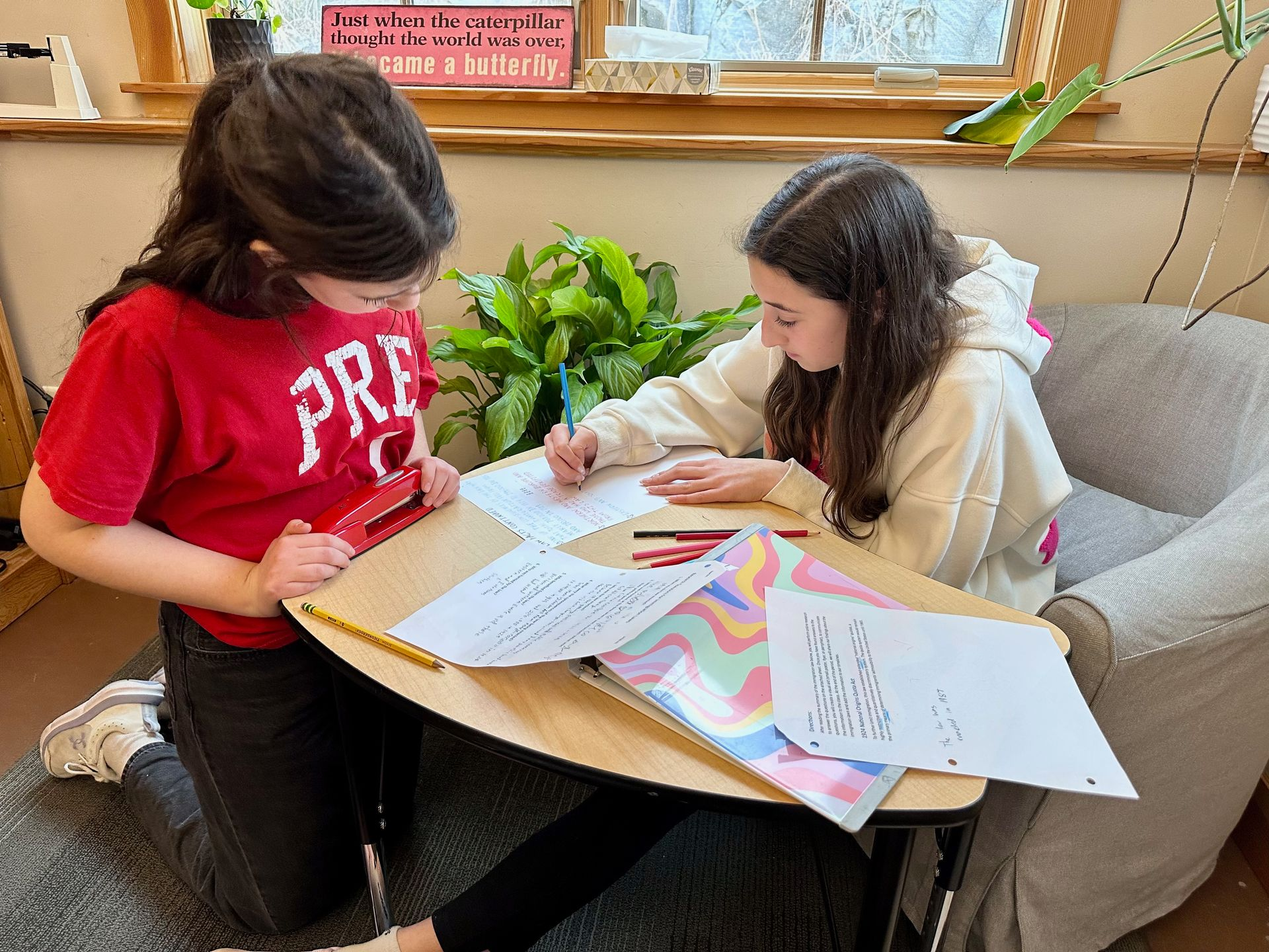 Image of two girls working together over books at a table