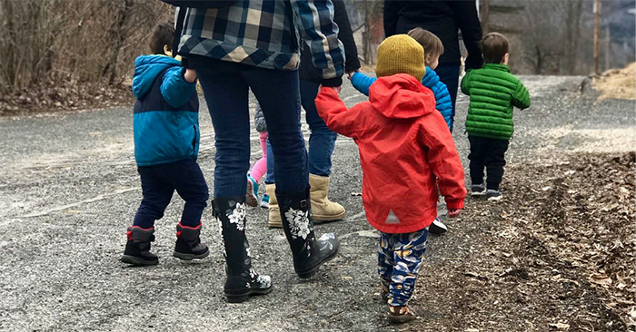 children from the toddler program walking holding hands while they walk with guides