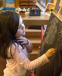 Preschool child drawing with chalk on an easel