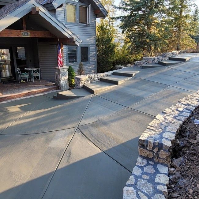 A concrete driveway with stairs leading up to a house