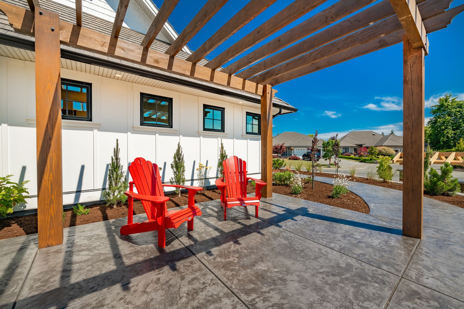 Two red chairs are sitting under a wooden pergola on a patio.