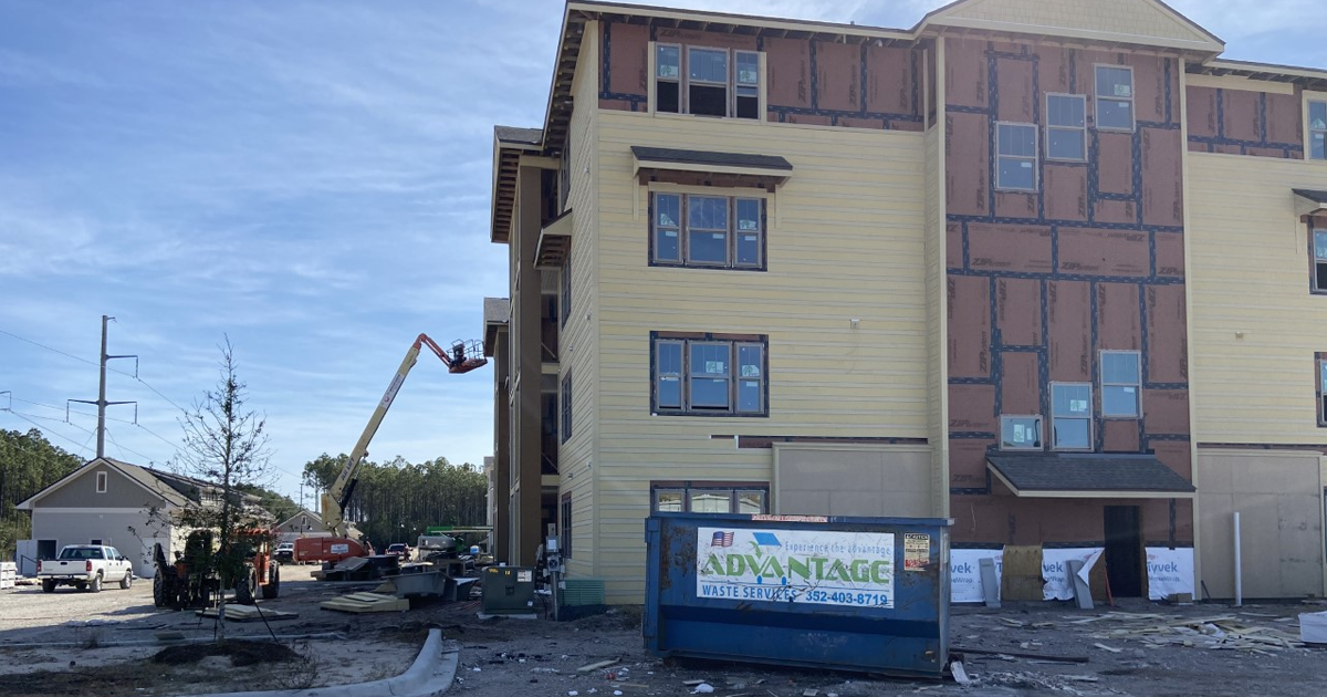 A large building under construction with a dumpster in front of it.