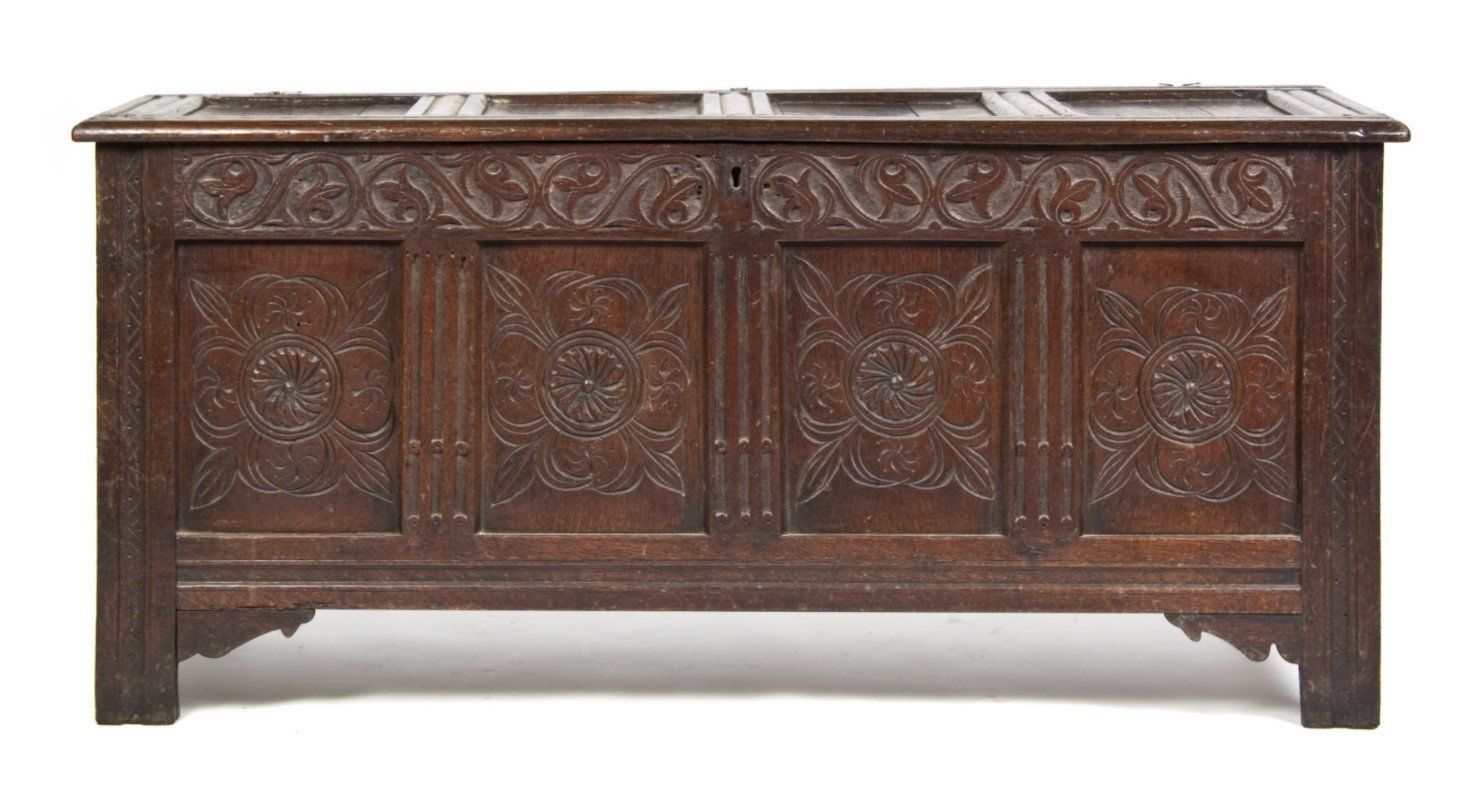 A wooden chest with a carved design on it is on a white background.