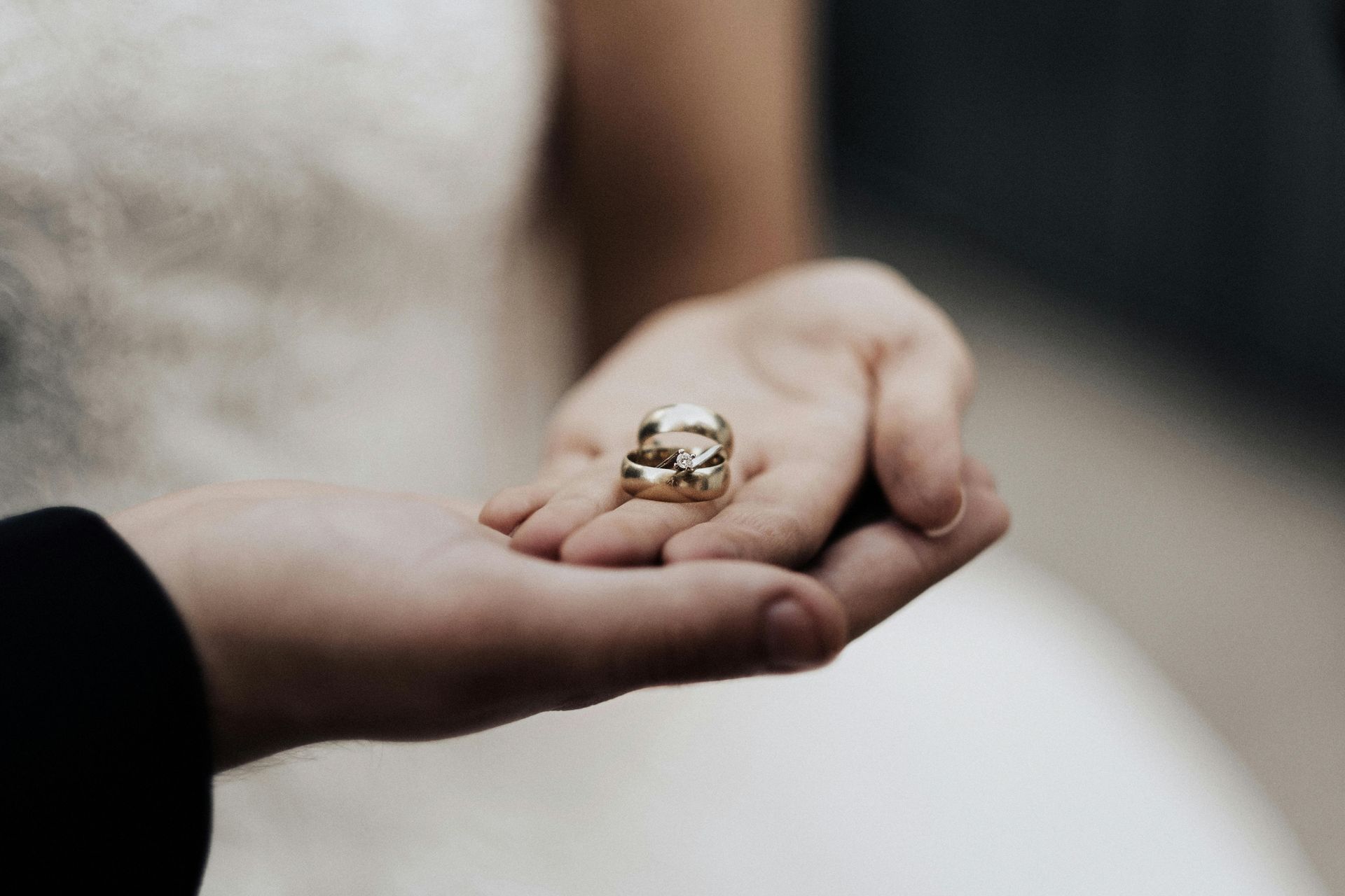 Wedding rings held in the palm of a hand, against a white dress, ready for the ceremony.