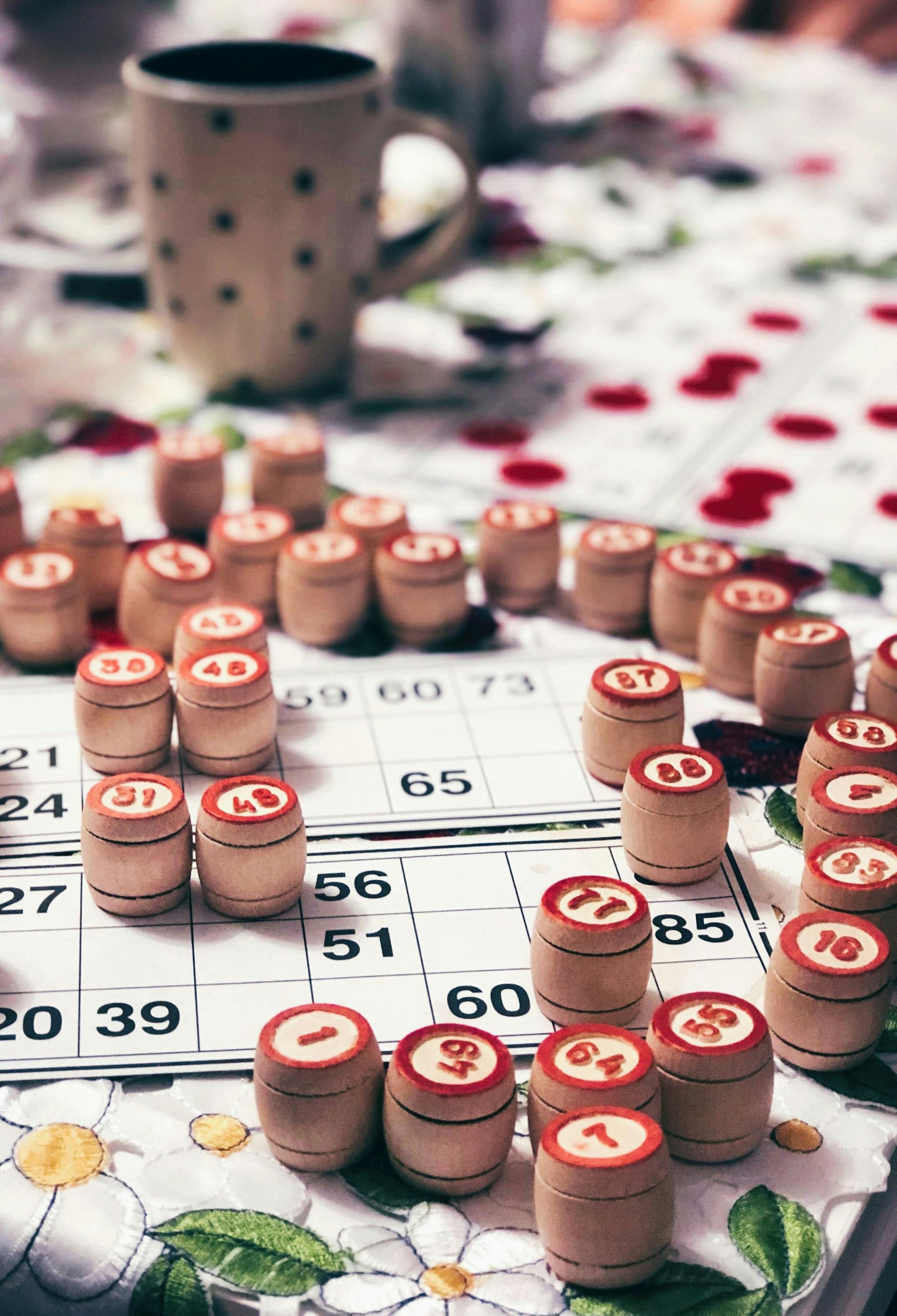 Close-up of a table with a bingo card, wooden barrels with numbers, and a mug.