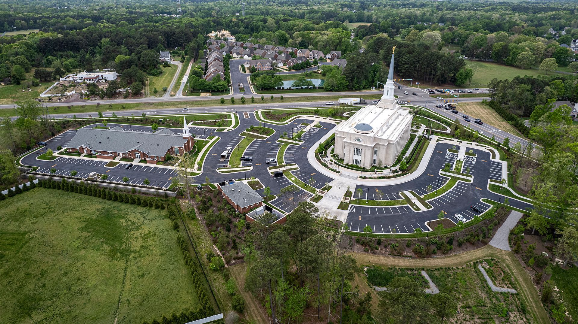 An aerial view of a large white building surrounded by parking lots and trees.